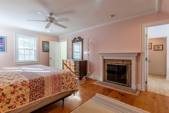 bedroom with a fireplace, light hardwood / wood-style floors, ceiling fan, and crown molding