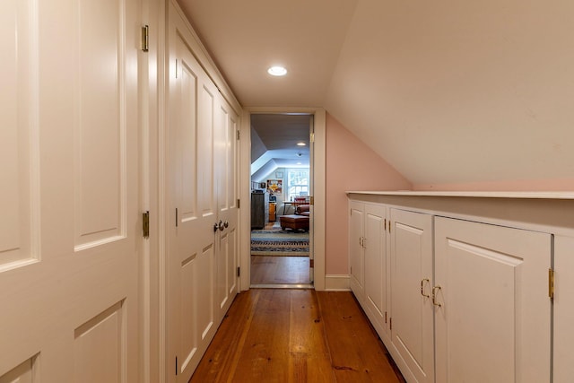 corridor with dark wood-type flooring and vaulted ceiling