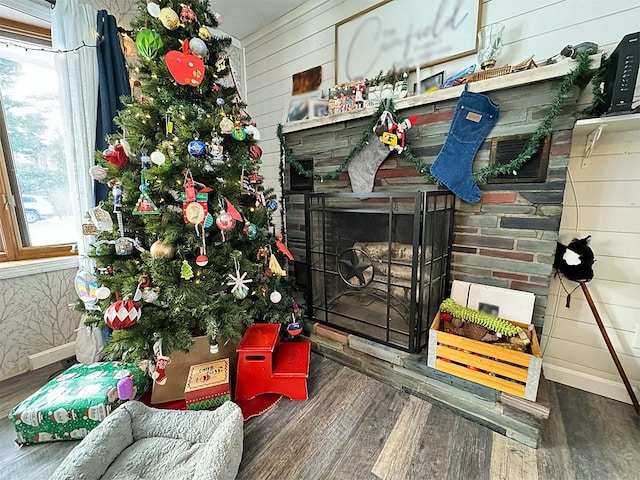 interior details with a stone fireplace, wood walls, and hardwood / wood-style flooring