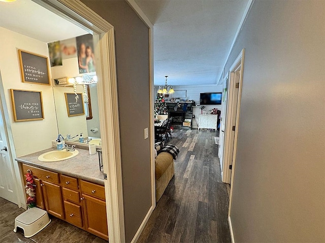 corridor featuring dark hardwood / wood-style flooring, sink, and an inviting chandelier