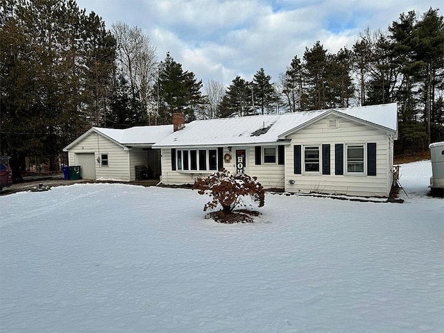 snow covered rear of property with a garage and an outdoor structure