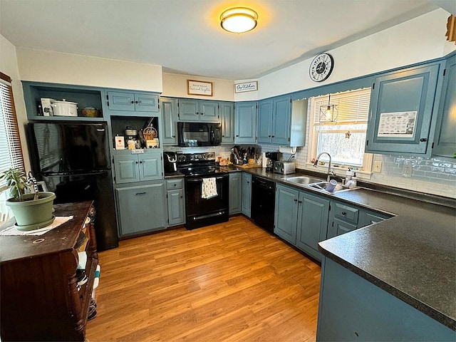 kitchen featuring blue cabinetry, sink, decorative backsplash, black appliances, and light wood-type flooring