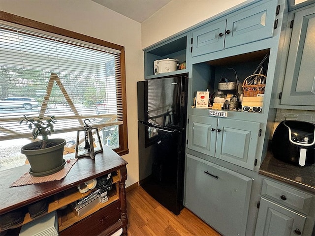 kitchen featuring black refrigerator, light hardwood / wood-style floors, and tasteful backsplash