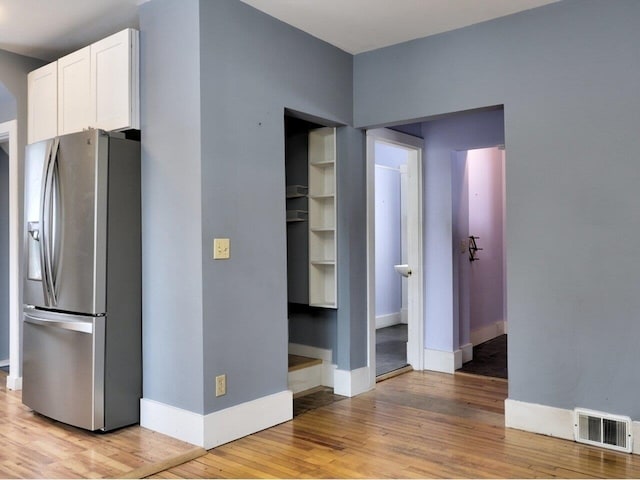 interior space with stainless steel fridge with ice dispenser, light hardwood / wood-style flooring, and white cabinets