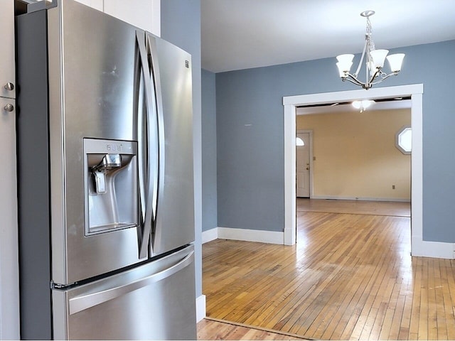 kitchen with a chandelier, stainless steel fridge, light hardwood / wood-style floors, and decorative light fixtures