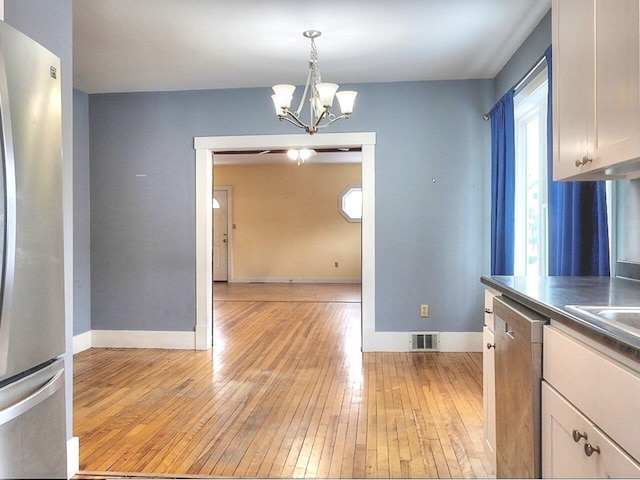 kitchen featuring pendant lighting, white cabinets, light hardwood / wood-style flooring, appliances with stainless steel finishes, and a chandelier