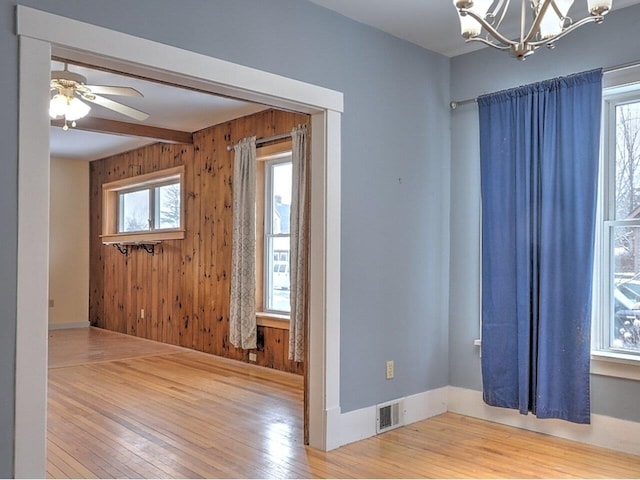 foyer featuring a wealth of natural light, wooden walls, wood-type flooring, and ceiling fan with notable chandelier