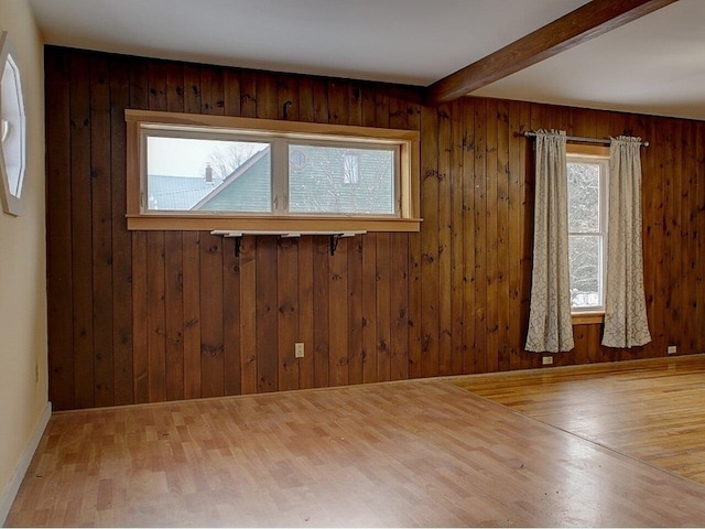 spare room featuring beam ceiling, hardwood / wood-style flooring, and wooden walls