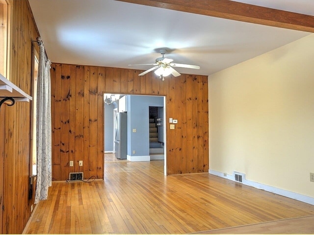 spare room featuring wood walls, ceiling fan, and light hardwood / wood-style floors