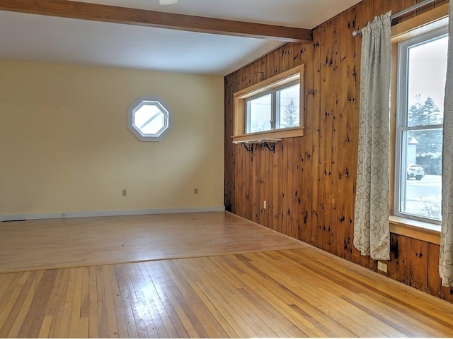 unfurnished room featuring hardwood / wood-style floors, wood walls, and beam ceiling