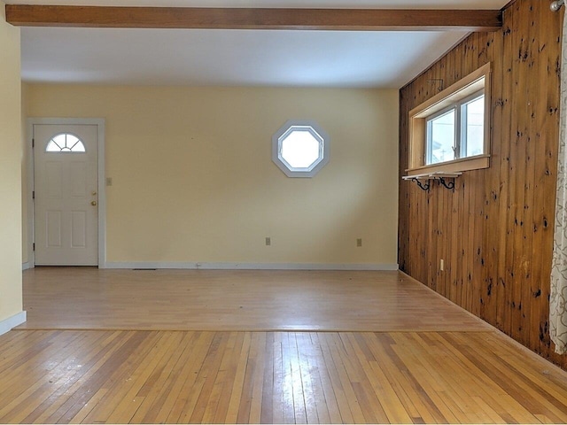 foyer with plenty of natural light, wood walls, beam ceiling, and light hardwood / wood-style flooring