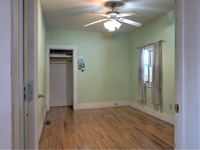 unfurnished bedroom featuring hardwood / wood-style flooring, ceiling fan, and a closet