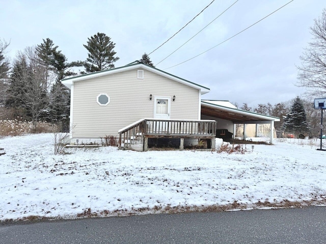 snow covered rear of property with a carport