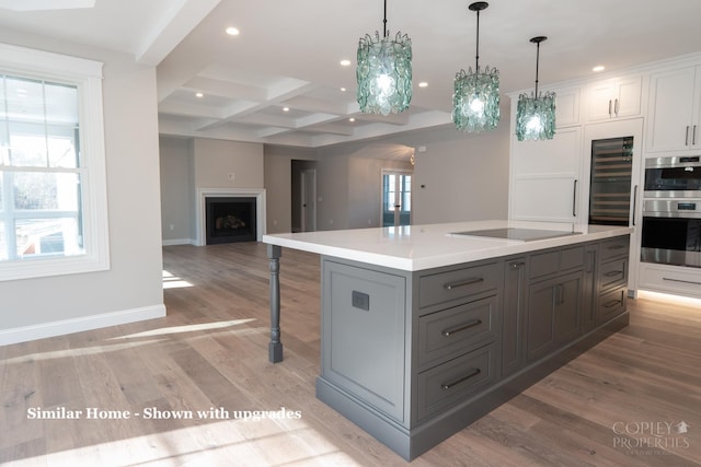 kitchen featuring white cabinets, a healthy amount of sunlight, a center island with sink, and coffered ceiling