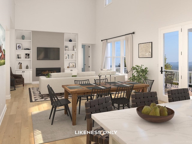 dining space with built in shelves, a towering ceiling, and light hardwood / wood-style floors