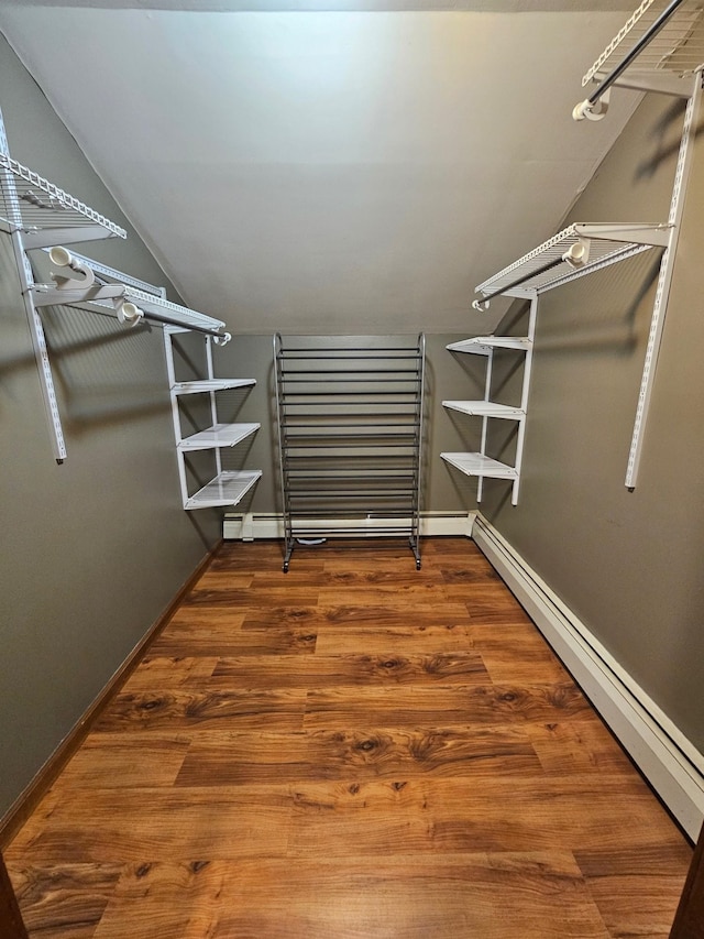 walk in closet with a baseboard heating unit, lofted ceiling, and wood finished floors