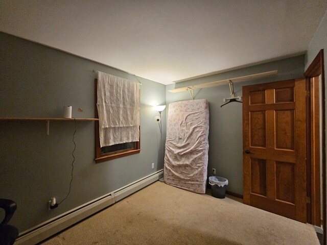 unfurnished bedroom featuring a baseboard heating unit, carpet floors, and baseboards