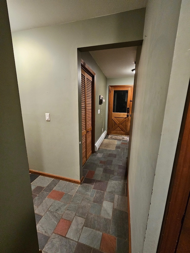 hall featuring baseboards and stone finish floor