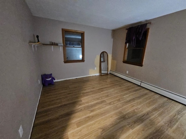 spare room with a baseboard heating unit and wood finished floors