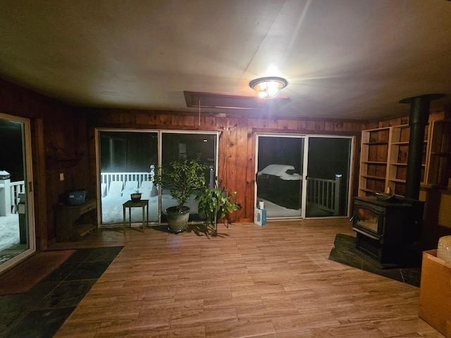 living area featuring attic access, wood finished floors, a wood stove, and wood walls