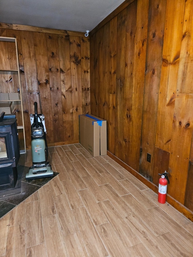 spare room featuring wooden walls, wood finished floors, and a wood stove