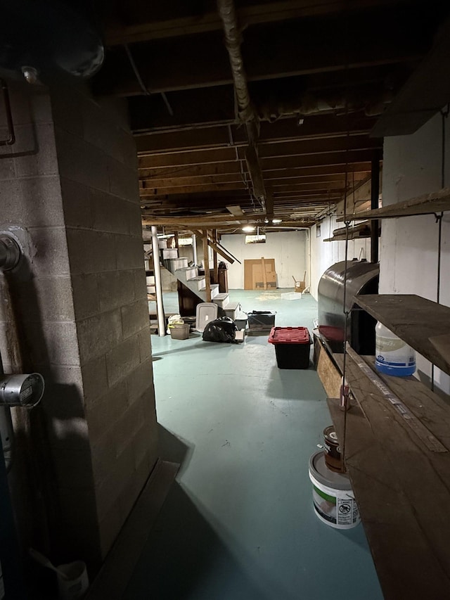 unfinished basement featuring heating fuel and concrete block wall