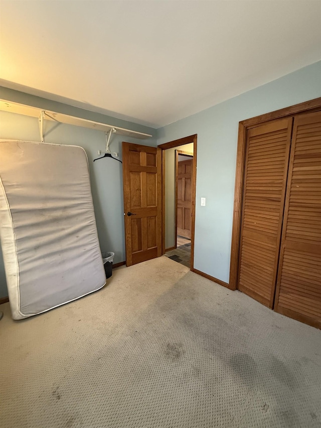 unfurnished bedroom with a closet, baseboards, and carpet