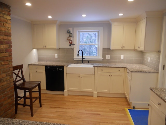 kitchen featuring light wood-type flooring, black dishwasher, light stone countertops, and sink