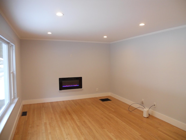 unfurnished living room with ornamental molding and light wood-type flooring