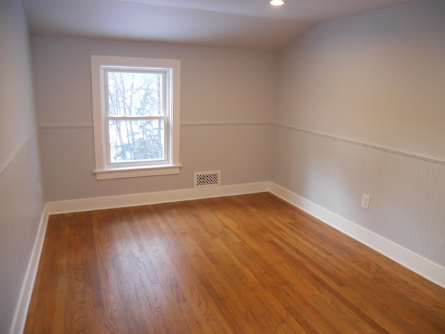 spare room featuring hardwood / wood-style flooring and lofted ceiling