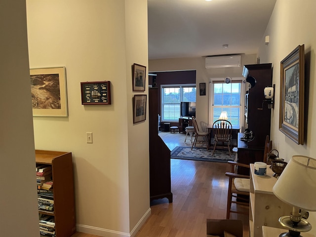 hallway with wood-type flooring and a wall unit AC