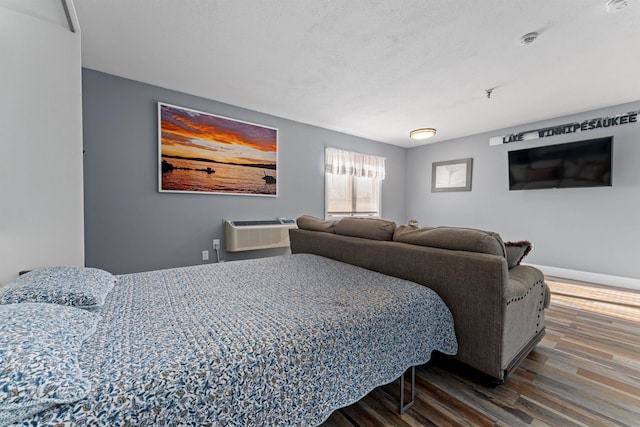 bedroom with hardwood / wood-style floors and a wall mounted AC