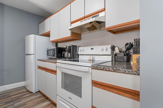 kitchen featuring dark stone counters, white cabinetry, dark hardwood / wood-style floors, and white appliances