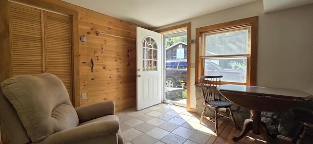 entryway with wooden walls and light tile patterned flooring