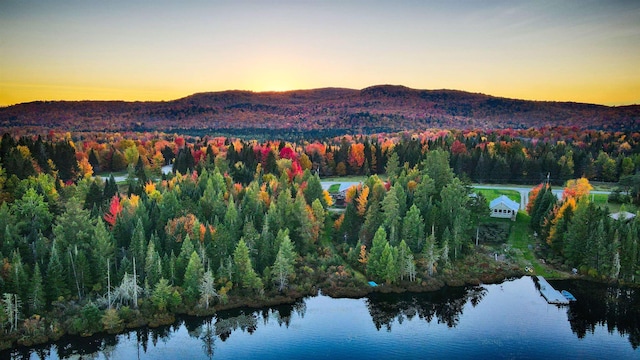 aerial view at dusk featuring a water and mountain view