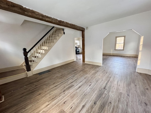 unfurnished living room featuring hardwood / wood-style floors and beamed ceiling