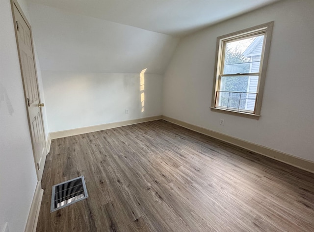 additional living space with hardwood / wood-style flooring and lofted ceiling