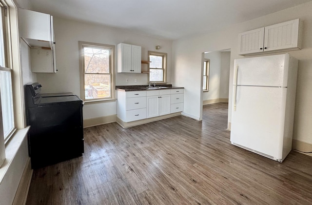 kitchen featuring washer / dryer, white cabinets, light wood-type flooring, and white refrigerator