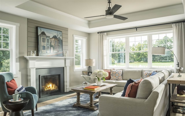 sunroom with ceiling fan, a large fireplace, a wealth of natural light, and a tray ceiling