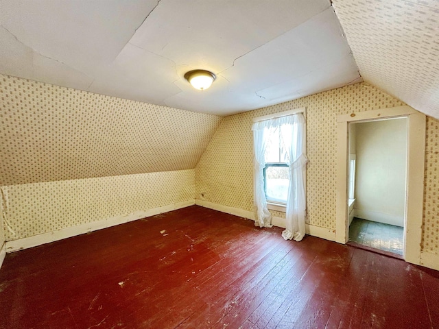 additional living space featuring lofted ceiling and dark hardwood / wood-style flooring