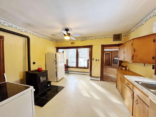 kitchen with a baseboard radiator, a wood stove, ceiling fan, and white refrigerator