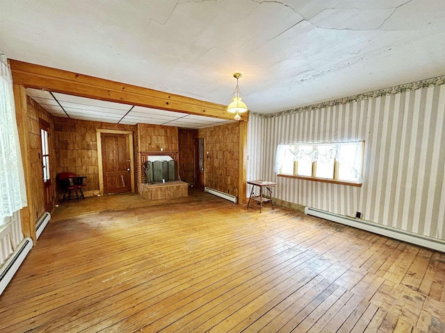 unfurnished living room with a baseboard heating unit, beam ceiling, and light wood-type flooring