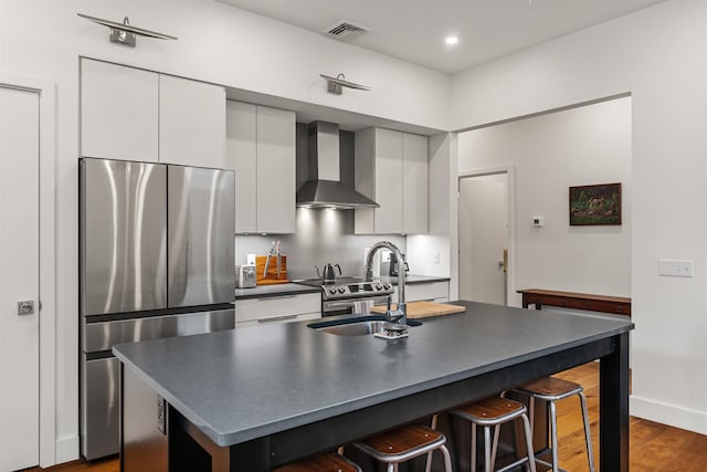 131 Main St Unit 2A-1, Burlington, VT 05401 - kitchen with stainless steel appliances, wall chimney range hood, white cabinetry, a breakfast bar area, and recessed lighting