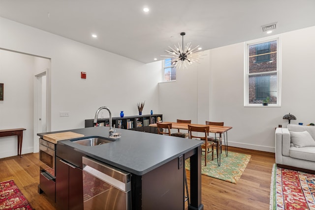 131 Main St Unit 2A-1, Burlington, VT 05401 - kitchen featuring stainless steel dishwasher, an island with sink, light wood-style flooring, a chandelier, and open floor plan