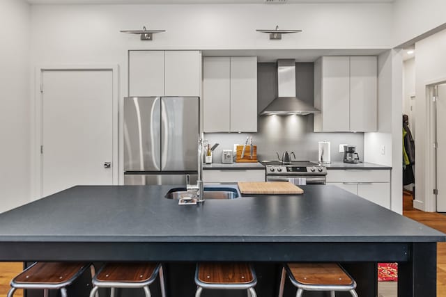 131 Main St Unit 2A-1, Burlington, VT 05401 - kitchen featuring wall chimney range hood, stainless steel appliances, modern cabinets, dark countertops, and white cabinetry