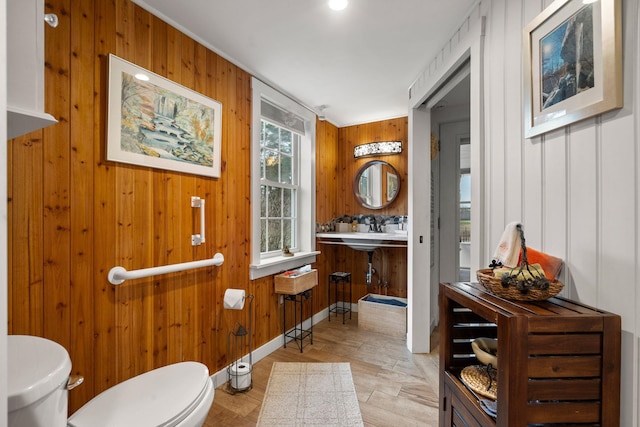 bathroom featuring wooden walls and toilet