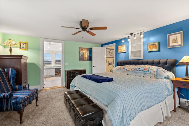 bedroom with ceiling fan, ensuite bathroom, light colored carpet, and track lighting