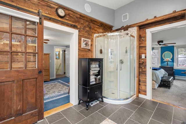 bathroom featuring a baseboard heating unit, a shower with door, ceiling fan, and wooden walls