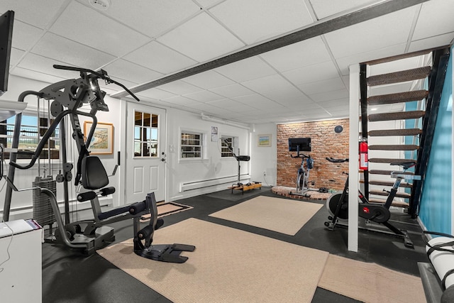 workout area with a drop ceiling, baseboard heating, and a wealth of natural light