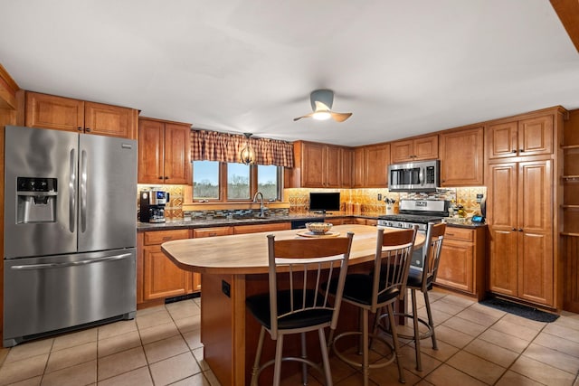 kitchen featuring sink, a center island, light tile patterned flooring, and appliances with stainless steel finishes